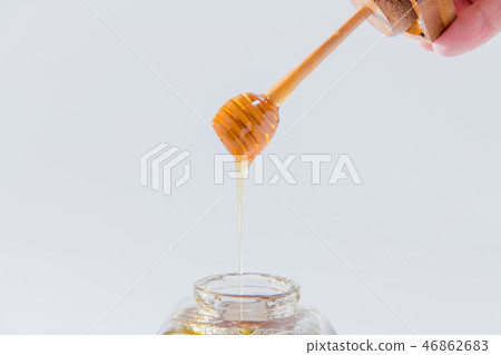 Honey drips from a wooden honey dipper on a white background 46862683