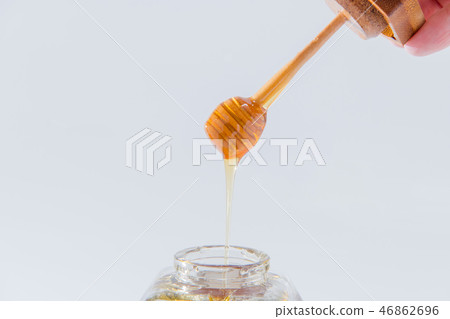 Honey drips from a wooden honey dipper on a white background 46862696