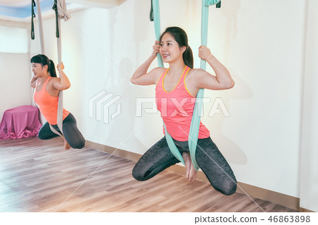 two happy young women doing anti gravity yoga two happy young women doing anti gravity yoga 46863898