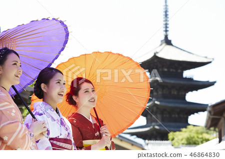 Three women in kimonos standing against a five-storied pagoda 46864830