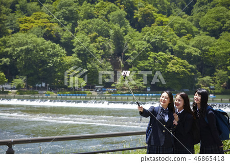 Two high school girls taking selfie with a selfie stick against the river Two high school girls taking selfie with a selfie stick against the river 46865418