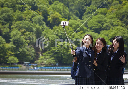 Two high school girls taking selfie with a selfie stick against the river 46865430