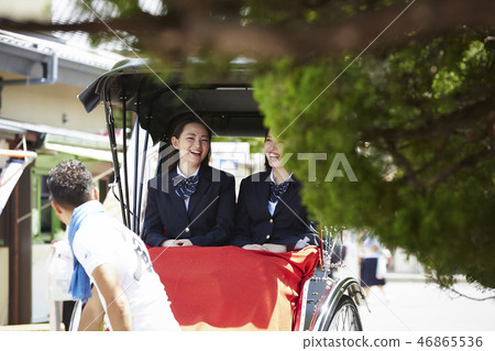 乘坐人力車的兩個高中女孩去在街道上 乘坐人力車的兩個高中女孩去在街道上 46865536