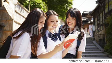 在手中走在城市的三個高中女孩與指南 在手中走在城市的三個高中女孩與指南 46865544