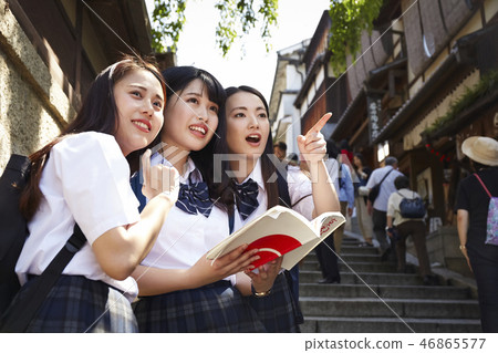 在手中走在城市的三個高中女孩與指南 在手中走在城市的三個高中女孩與指南 46865577