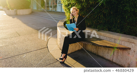 Secretary talking by smartphone with document case in   outdoors 46880429