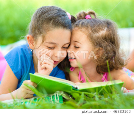 Two little girls are reading book 46883163