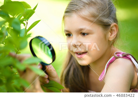 Girl is looking at tree leaves through magnifier Girl is looking at tree leaves through magnifier 46883422