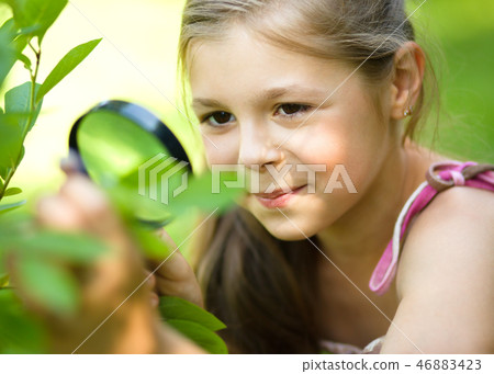 Girl is looking at tree leaves through magnifier 46883423