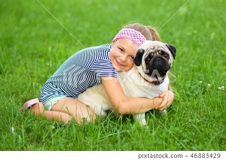 Little girl and her pug dog on green grass Little girl and her pug dog on green grass 46883429