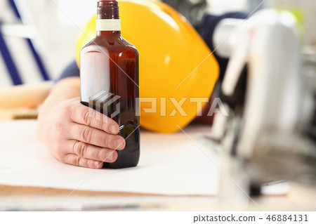 Arm of drunken worker in yellow helmet Arm of drunken worker in yellow helmet 46884131