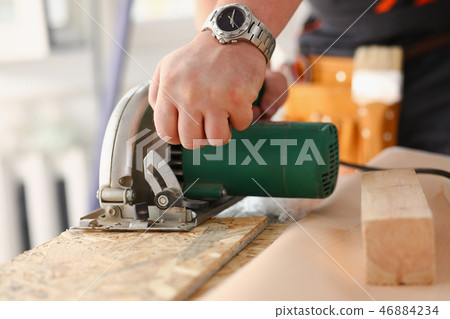 Arms of worker using electric saw Arms of worker using electric saw 46884234
