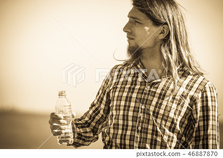 Man long hair relaxing by seaside drinking water 46887870