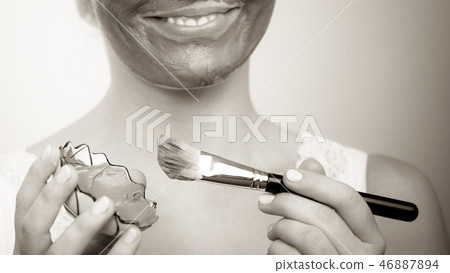 Woman applying with brush clay mud mask to her face 46887894