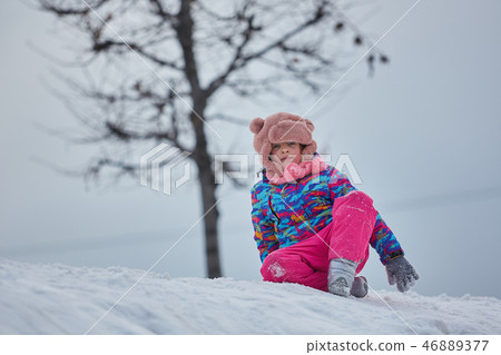 little girl riding on snow slides in winter time 46889377