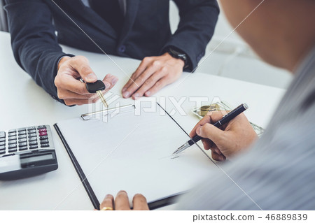 Salesman send key to customer after man signing car document con Salesman send key to customer after man signing car document con 46889839