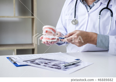 Dentist hand holding of jaw model of teeth and cleaning dental w 46889882