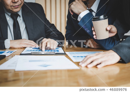 Executive team discussing the charts and graphs working in busin Executive team discussing the charts and graphs working in busin 46889976