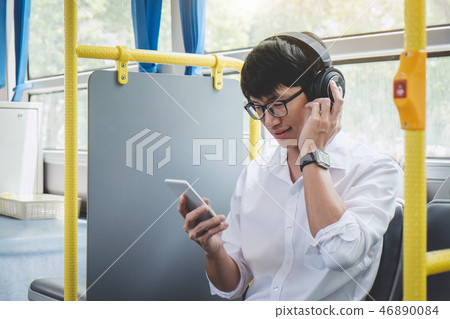 Young Asian man traveler sitting on a bus listening to music on Young Asian man traveler sitting on a bus listening to music on 46890084