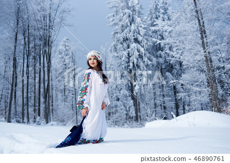 Young woman in white dress embroidered with floral design, colorful kerchief with blue shoulder bag. 46890761