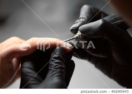 Close-up of professional beautician hands working with electric drill file on client fingernails. 46890945
