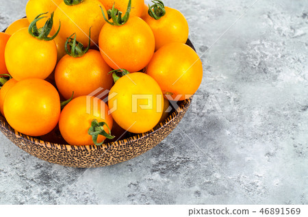 Golden yellow cherry tomatoes in wooden bowl Golden yellow cherry tomatoes in wooden bowl 46891569