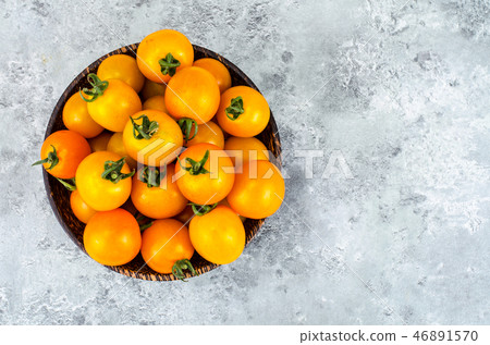 Golden yellow cherry tomatoes in wooden bowl Golden yellow cherry tomatoes in wooden bowl 46891570