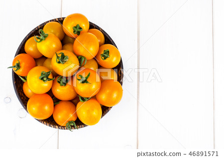 Golden yellow cherry tomatoes in wooden bowl Golden yellow cherry tomatoes in wooden bowl 46891571