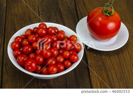 Small red cherry tomatoes in white bowl on wooden Small red cherry tomatoes in white bowl on wooden 46892553