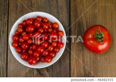 Small red cherry tomatoes in white bowl on wooden Small red cherry tomatoes in white bowl on wooden 46892555