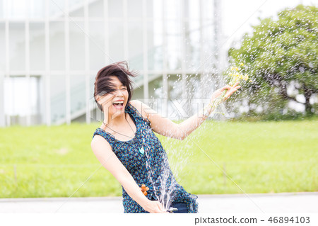 Pretty arafif woman playing with water in the park 46894103