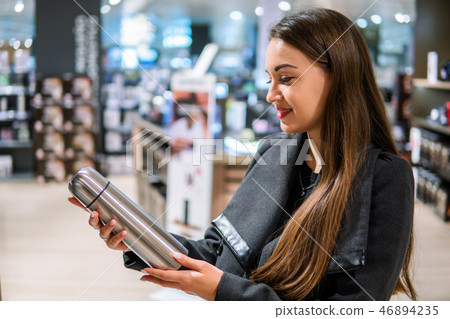 woman choosing thermos bottle in a store supermarke woman choosing thermos bottle in a store supermarke 46894235