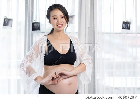 pregnant woman holding hands in heart shape on belly pregnant woman holding hands in heart shape on belly 46907297
