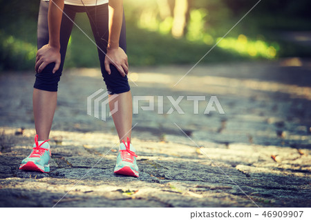 Tired female runner taking a rest after running Tired female runner taking a rest after running 46909907