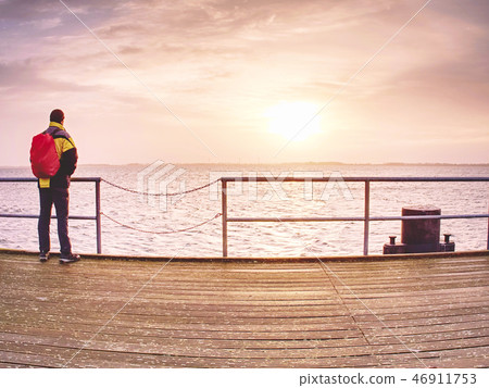 Man tourist in autumn mist on pier above sea 46911753