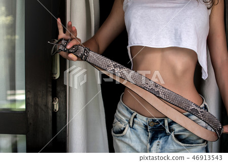 Fashion luxury snakeskin leather belts outdoors. Girl holsing Python belts on expensive villa. top Fashion luxury snakeskin leather belts outdoors. Girl holsing Python belts on expensive villa. top 46913543