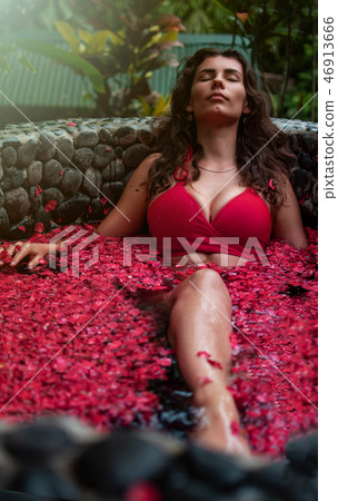 Young woman relaxing in outdoor flower bath, organic skin care, luxury spa in jungle. Beauty and 46913666