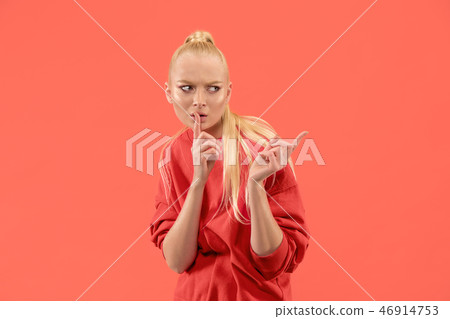 The young woman whispering a secret behind her hand over coral background The young woman whispering a secret behind her hand over coral background 46914753