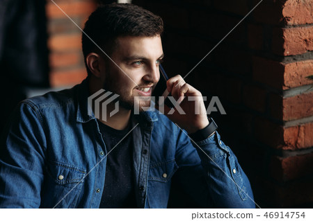 Young businessman look at the phone in cafe while he use a laptop Young businessman look at the phone in cafe while he use a laptop 46914754