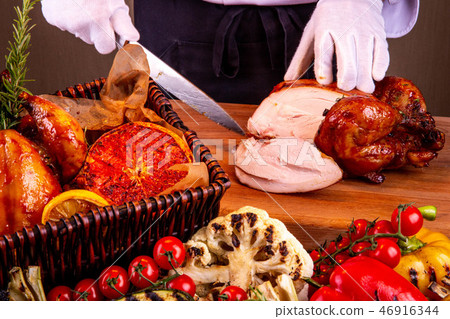 Cutting of chicken by the chef on a chopping board Cutting of chicken by the chef on a chopping board 46916344