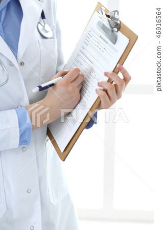 Female doctor using medical form on clipboard closeup. Physicianat work in hospital or clini Female doctor using medical form on clipboard closeup. Physicianat work in hospital or clini 46916564