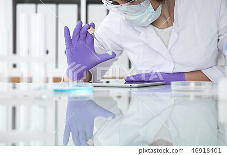 Close-up of professional female scientist in protective eyeglasses making experiment with reagents Close-up of professional female scientist in protective eyeglasses making experiment with reagents 46918401