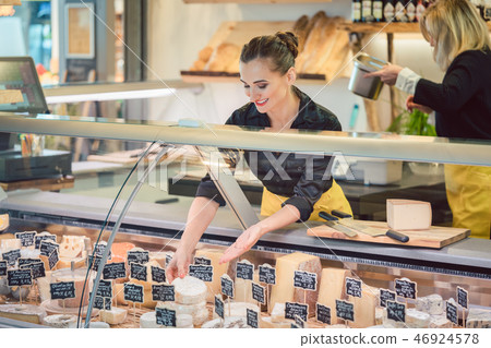 Shop clerk woman sorting cheese in the supermarket display 46924578