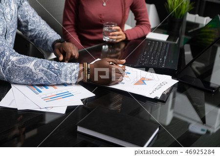 two young black people discuss their business using diagrams sitting at Desk in the office two young black people discuss their business using diagrams sitting at Desk in the office 46925284