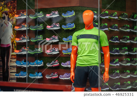 Male mannequin in a green T-shirt in the shop window of a sporting goods store on the background of 46925331