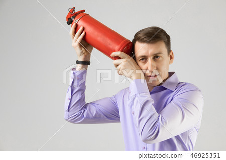 young man put a fire extinguisher to his head isolated on light background young man put a fire extinguisher to his head isolated on light background 46925351