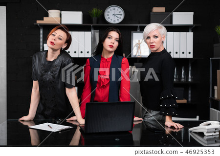 Three business women stand near Desk in office 46925353