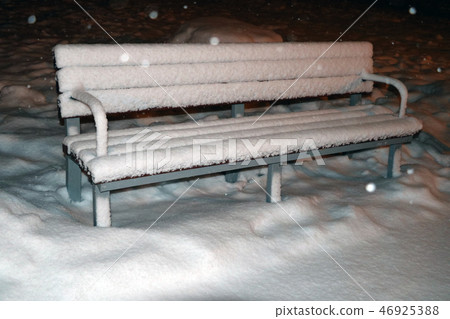 Snow-covered bench in the evening park. Winter. Snow-covered bench in the evening park. Winter. 46925388