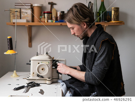 Handsome man tailor sew fur on furrier machine in workshop 46926291
