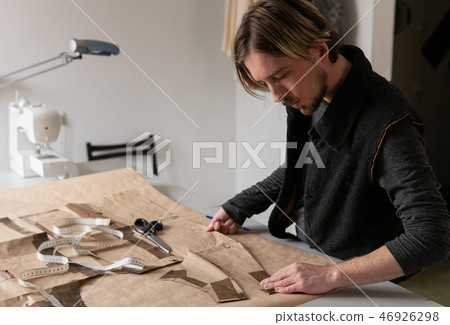 Male tailor creating clothing pattern while working at workplace Male tailor creating clothing pattern while working at workplace 46926298